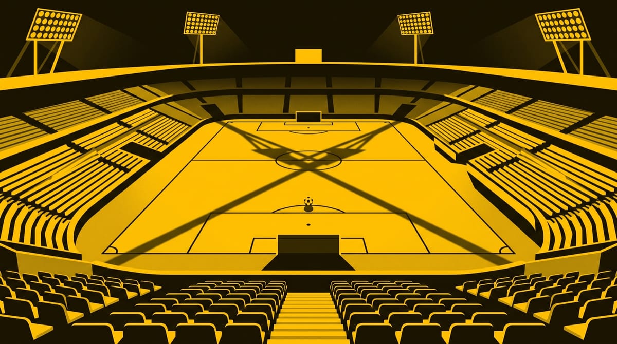 An empty football stadium at night after the last match, seen from high in the stands.