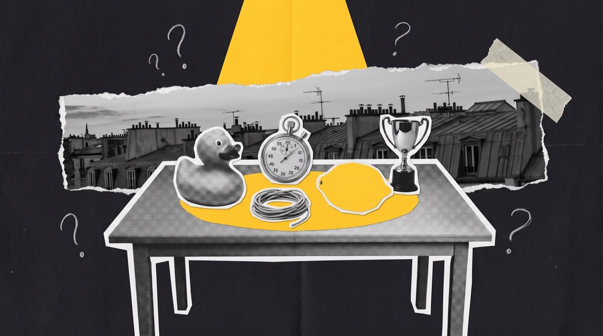 Paper collage of a bare studio table under a yellow spotlight holding a rubber duck, stopwatch, string, lemon and trophy, with Paris rooftops at dusk behind.